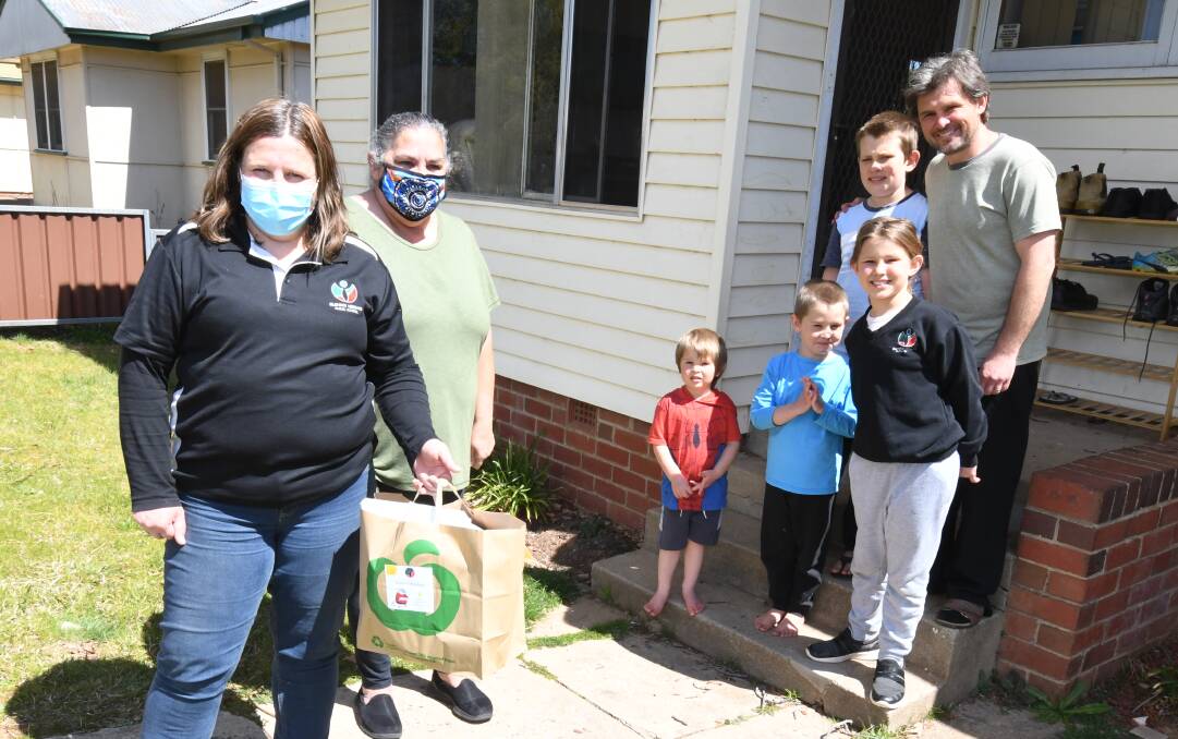 Rachel Livingstone and Sharon Horton drop off a holiday pack to the Harris family - Michael, James, Anthony Jnr, Sarah and dad Anthony Snr Harris.
