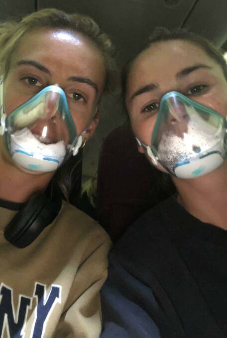 Gabi Nance and Kalindi Commerford wear facemasks on the flight home from Perth. Photo: Supplied