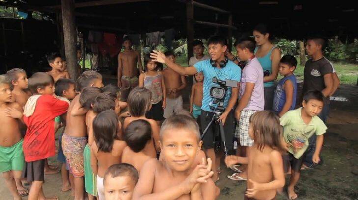 Romeu Iximaw????teri Yanomami (behind the camera) and Silvano Ironasiteri Yanomami to his right, organise Yanomami children for a video shoot.