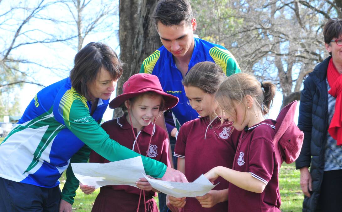 LEAD THE WAY: Elaine and Robert Bennett from The Goldseekers give Georgie Taberner, Justice Robinson and Makayla McEvoy from Borenore Public School a few directions. Photo: JUDE KEOGH 0618orienteer9
