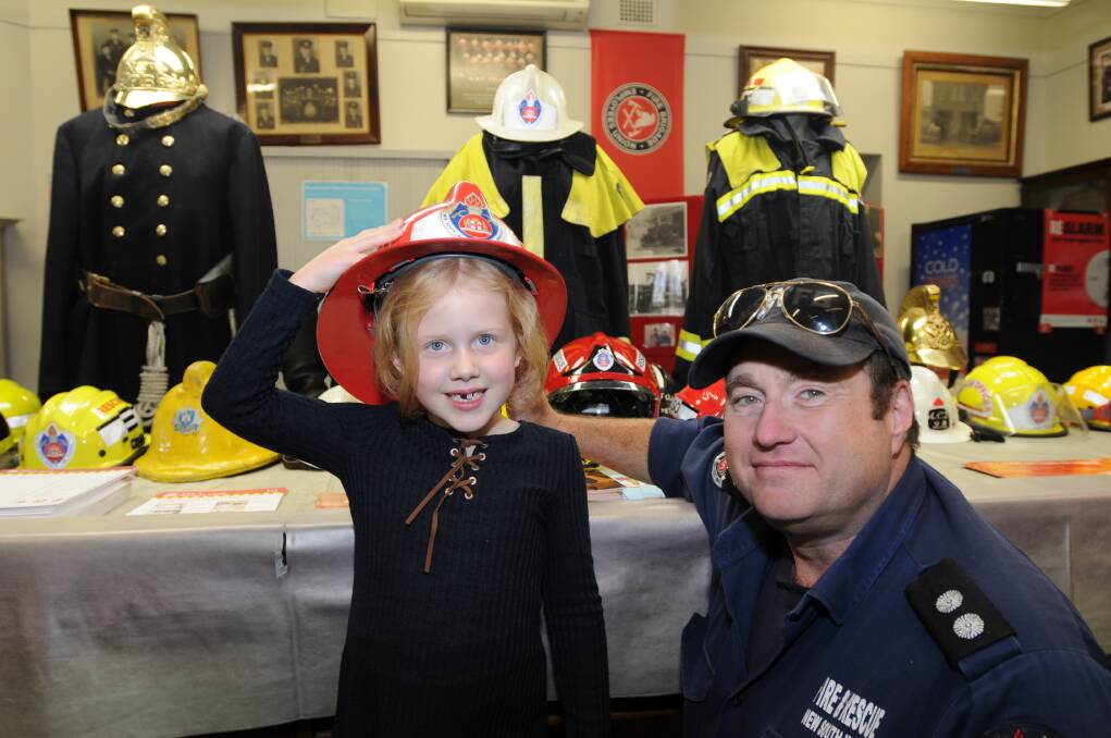 TRYING ON FOR SIZE: Holly Wylde, 6, tries on a firefighter helmet with station officer Andrew Henderson at the Orange Fire Station open day on Saturday. Photo: STEVE GOSCH
