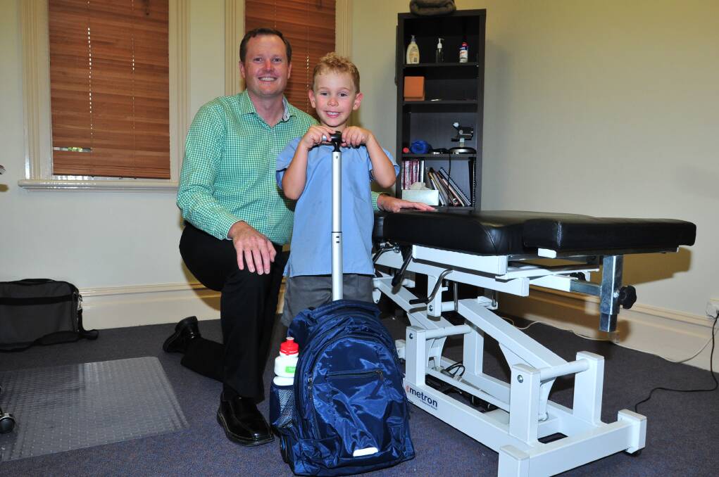 GIVING SUPPORT: Body and Spine Solutions chiropractor Andrew Blyth helps five-year-old Tommy Parolin will his rolling school bag. Photo: LUKE SCHUYLER
0210lsbackpack2
