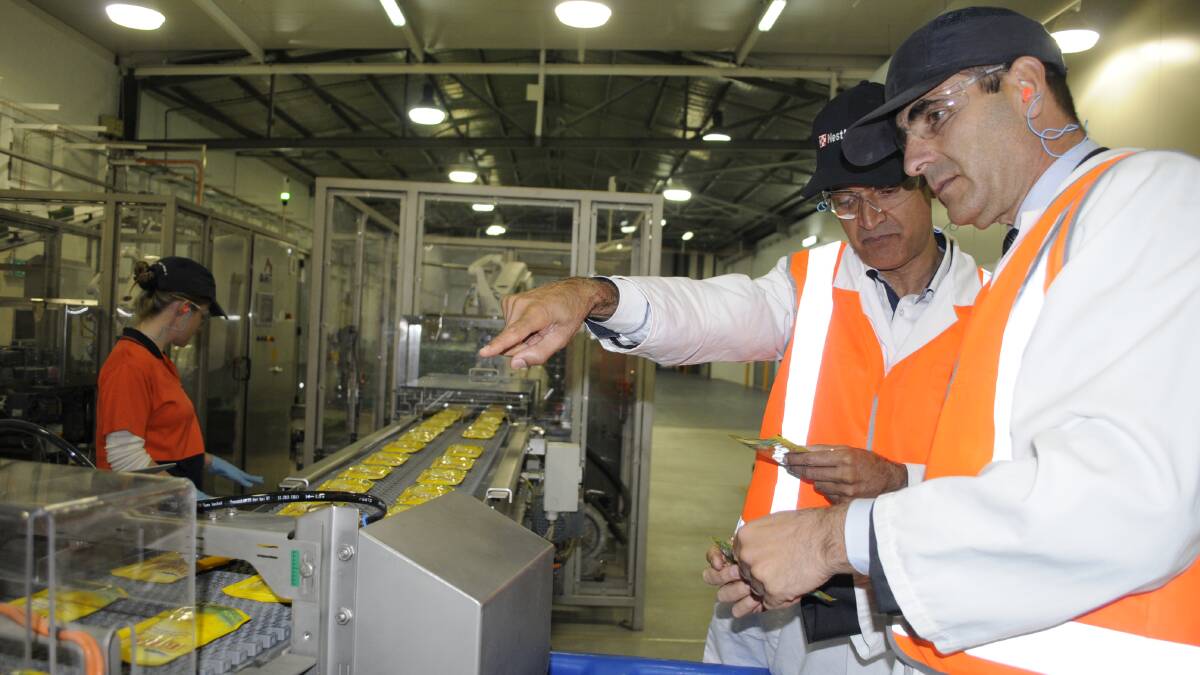JOBS BOOST: Nestle Purina employee Clare Stait works while the company’s vice president of operations Suleman Khan and president Rafael Lopez inspect some of the plant’s latest productions yesterday. Photo: CHRIS SEABROOK 101414cnes4