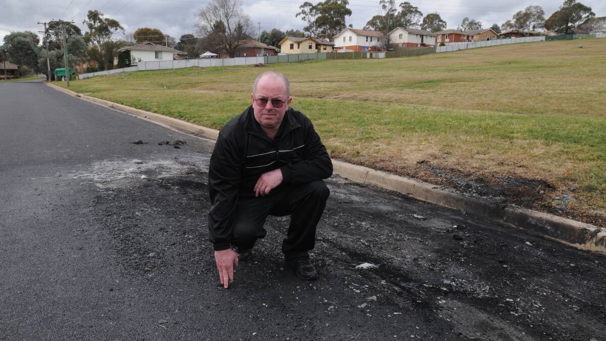 BURNING ISSUE: Andrew Lennard says he has had enough of burnt-out vehicles being left in suburban streets for weeks, only to have them leave a black mark on the road when they’re towed. Photo: STEVE GOSCH         0821sgbowen1