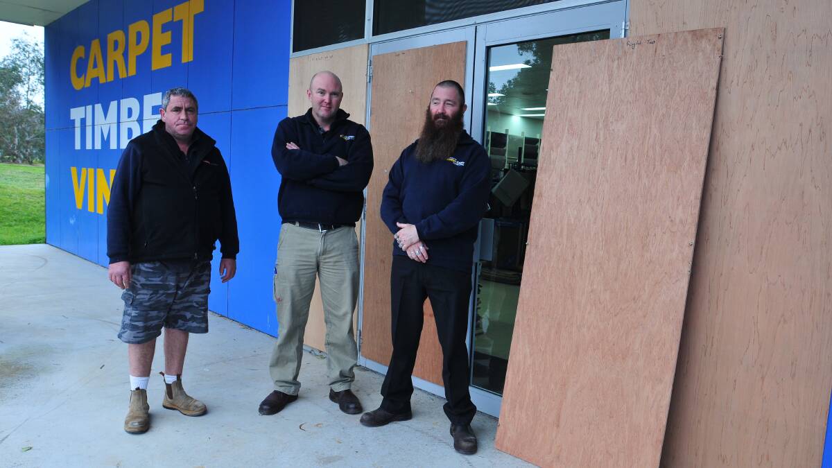 FED UP: Carpet Court's owner-manager Craig Buckley (centre) with employees Rod McEvoy and Dane Parker. Mr Buckley says he'll prosecute vandals responsible for repeated attacks on his store. Photo: JUDE KEOGH.