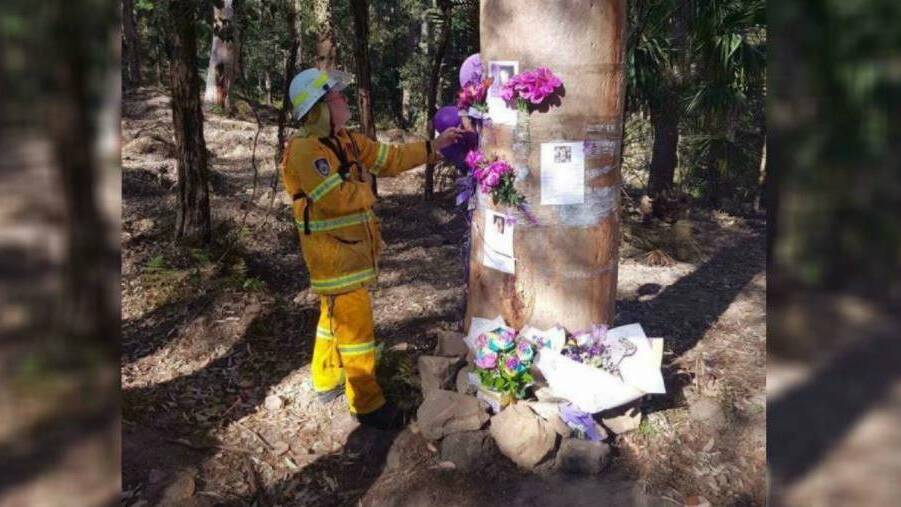 A Rural Fire Service volunteer beside the memorial tree after it escaped a bushfire in September, 2017. Picture: NSW Rural Fire Service Sutherland Shire

