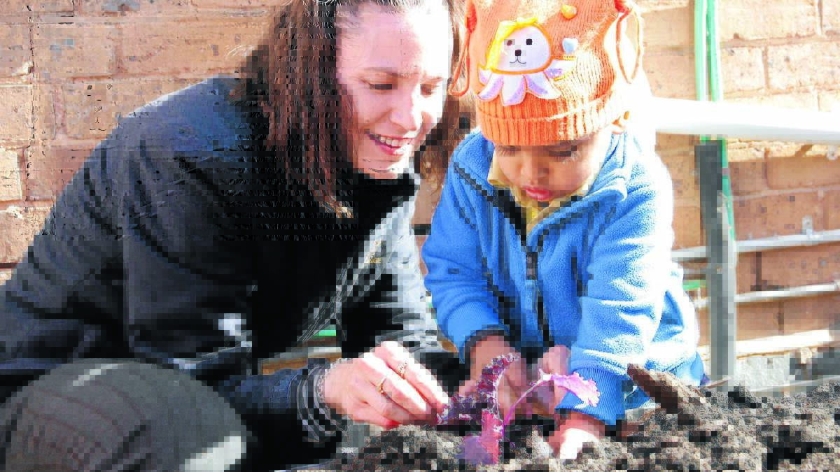 EAT YOUR GREENS: Childcare worker Amy Kjoller and Prithu planting the first vegetable seedlings in the Orange occasional childcare’s new vegetable garden.  Photo: MEGAN FOSTER                                           						               0723OOCCMF5