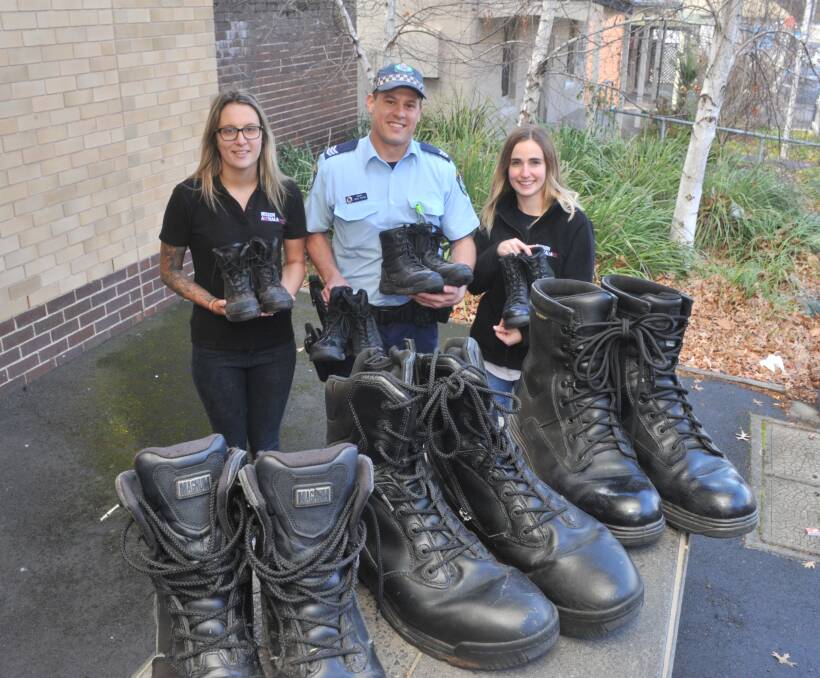 WALKING BOOTS: Sergeant Greg Payne hands over spare boots to help city's homeless to Mission Australia case workers Jess Wright (left) and Kelsey Lew. Photo: JUDE KEOGH 0816jkboots1