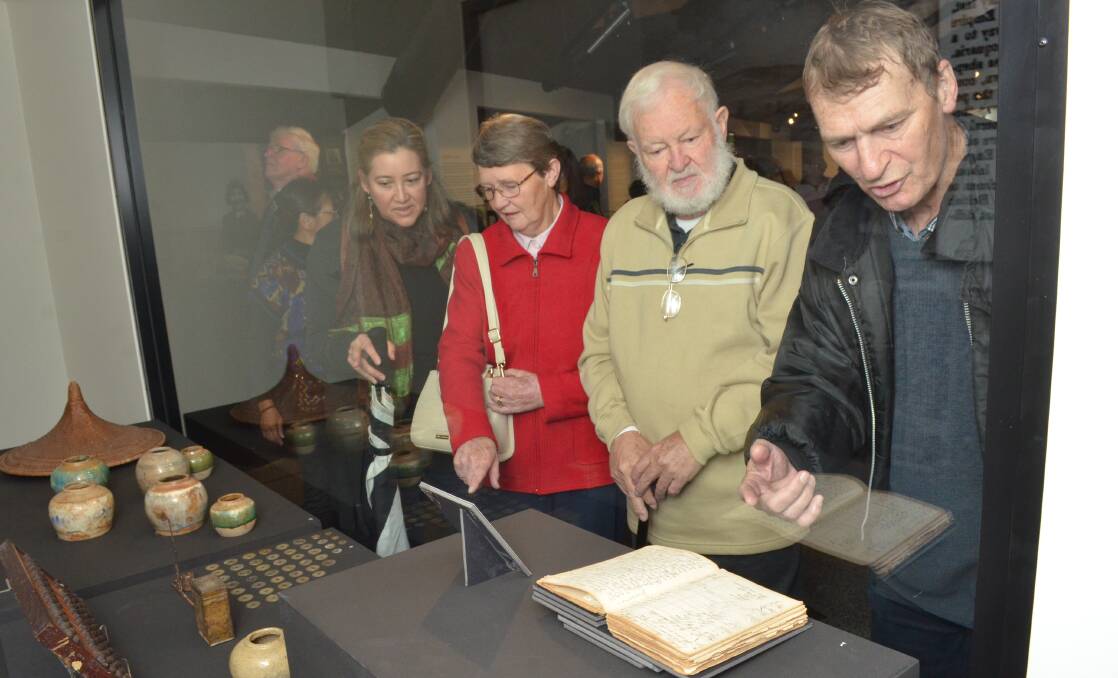 BEHIND THE LOOKING GLASS: Kira Brown, Marie and Phillip Schmich and Barry McGowan examine the exhibition. Photo: DECLAN RURENGA 0519drjourneys1