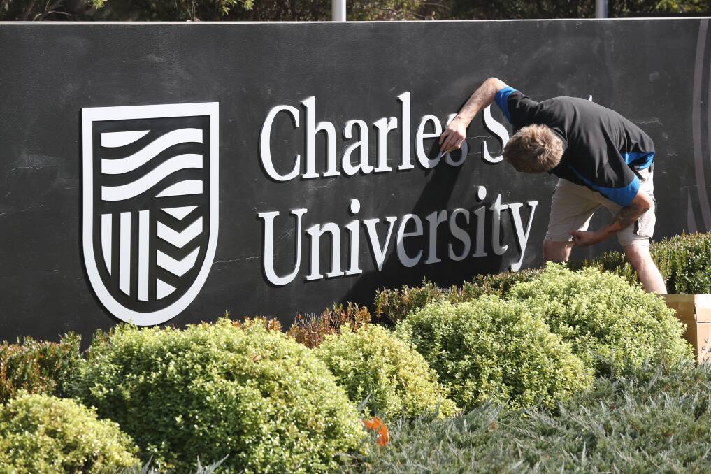 NEW LOOK: Workers installing the new logo sign at Charles Sturt University's entrance on Wednesday morning. Photo: PHIL BLATCH 050119pbcsu2
