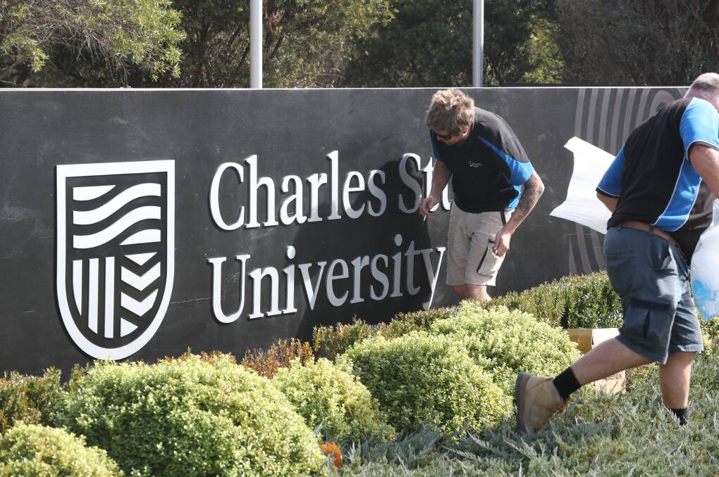 NEW LOOK: Workers installing the new logo sign at Charles Sturt University. Photo: PHIL BLATCH 050119pbcsu1