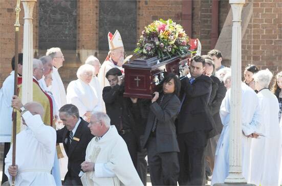 SAYING FAREWELL: Pallbearers carry the coffin of Archdeacon Norman Kempson from Holy Trinity yesterday. Photo: JUDE KEOGH                        0925funeral2
