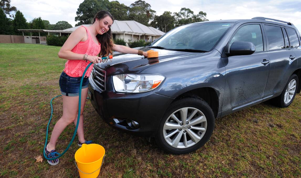 WATER WISE: Emily Collins washes the car on the lawn, complying with Orange City Council restrictions. Photo: STEVE GOSCH