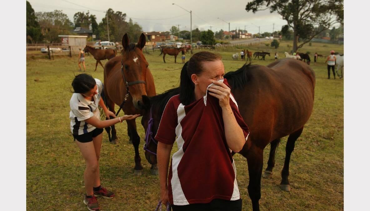 Sarah Wenn and Joanne Page calm their horses on a paddock next to Lake Road which is about 300m from the fire front. Photo: Max Mason-Hubers MMH.