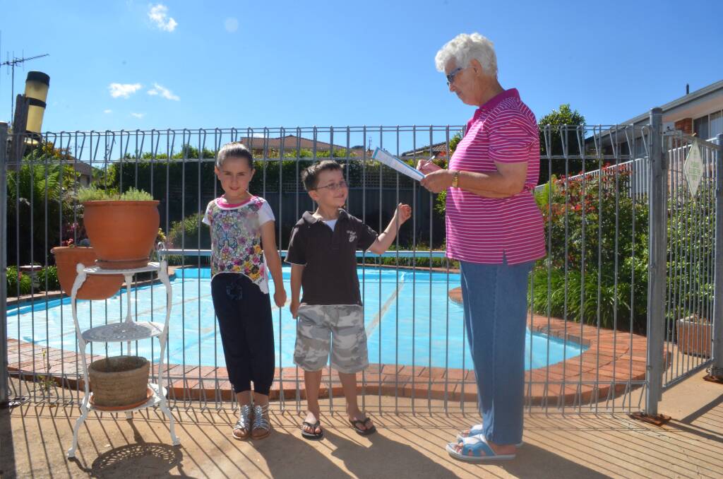 REGISTER FOR SAFETY: Robyn Wright with her grandchildren Eloise, 7, and Toby Middleton, 4, completing a safety check list to ensure her pool complies with regulations in the lead-up to all pool owners being required to register their pool on a state-wide list. Photo: NADINE MORTON                                                                             1119nmpool1 to 4