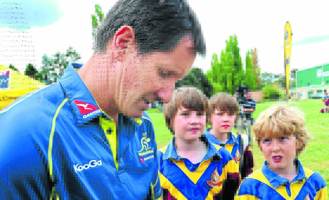 SIGNING UP: Robbie Deans signing autographs for Aden and Noa Fraser and Jock Clement at Endeavour Oval yesterday. Photo: Steve Gosch0403sgrugby3